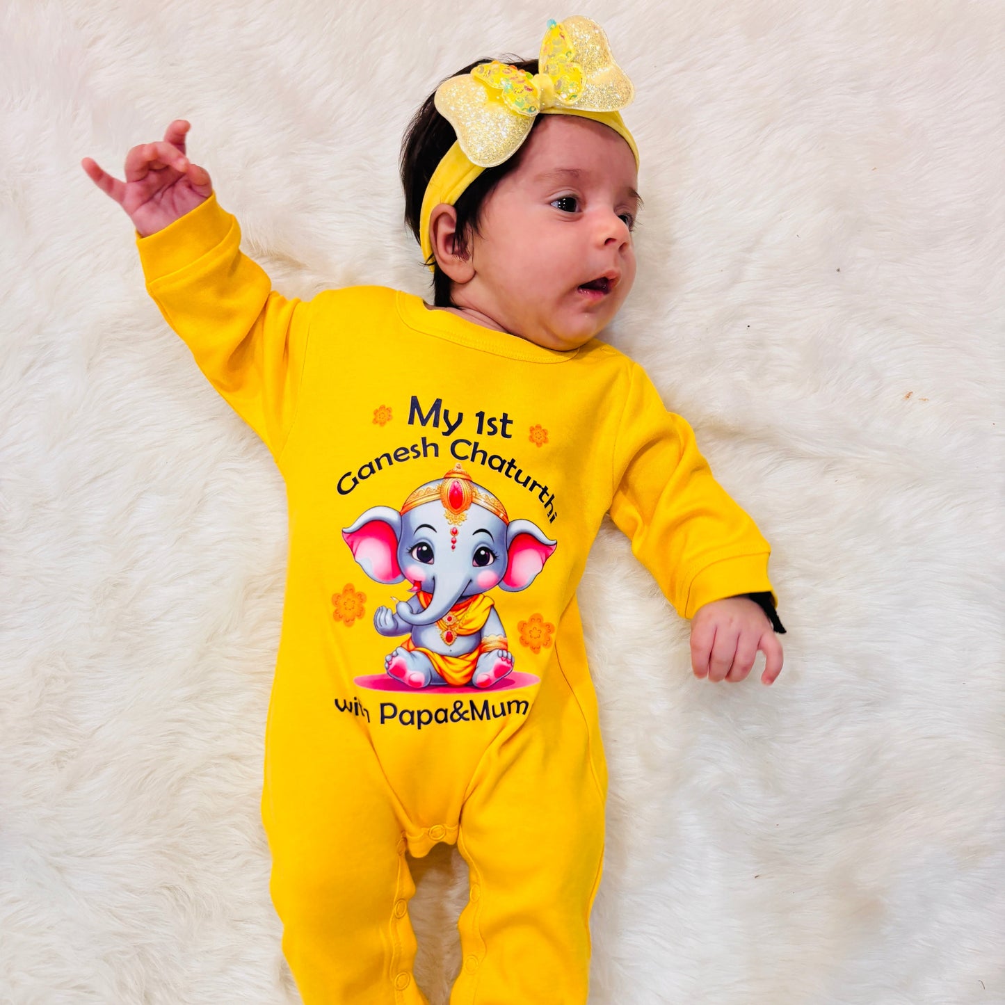 Baby in a yellow outfit with Ganesh Chaturthi design on a white background