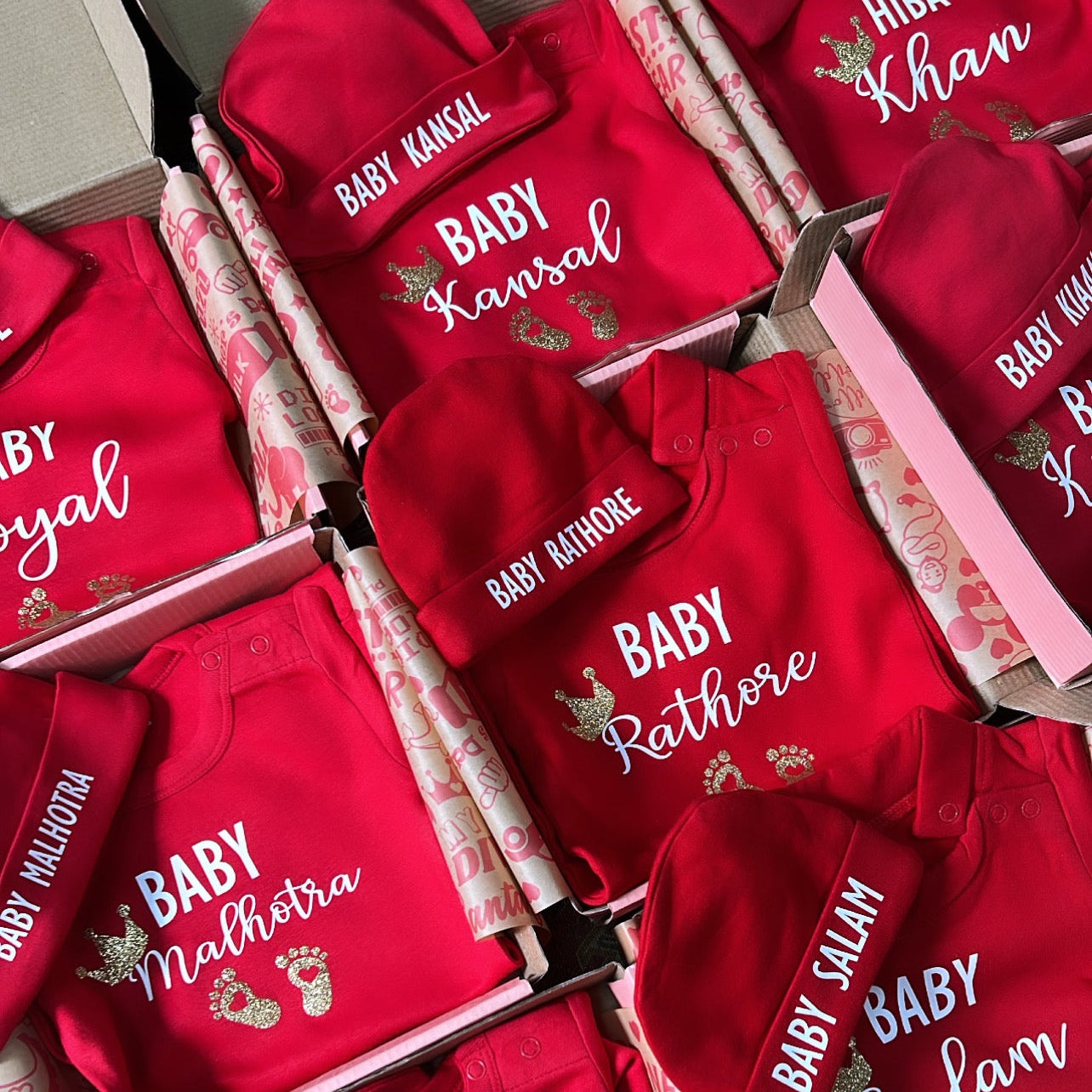 Red baby outfits with personalized names on a patterned surface