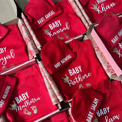Red baby outfits with personalized names on a patterned surface