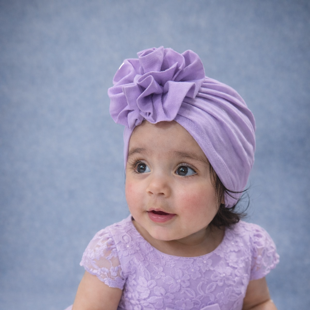 Baby in a purple dress and headband against a gray background
